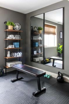 a mirror sitting on top of a wall next to a gym equipment rack filled with dumbs