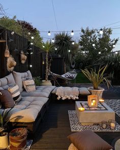 an outdoor living area with couches, tables and lights