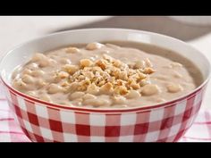 a red and white bowl filled with oatmeal on top of a checkered table cloth