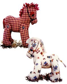 two stuffed horses are standing next to each other on the ground, one is white and the other is red