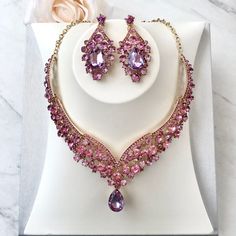 Purple is a favorite wedding color, and it can go well for Spring as well as Winter events. In line with the latest wedding trends, this beautiful three-piece bridal jewelry set is adorned with intricately faceted purple rhinestone crystals that capture the light from every angle with a perfectly translucent appeal. All pieces are rhodium plated for a flawless finish which enhances the intricate detailing and conveys a modern take on old elegance. Necklace: 17" (approx. 43cm) long with a 2" (app Purple Crystal Jewelry Sets For Wedding, Pink Crystal Jewelry Sets For Formal Occasions, Formal Pink Crystal Jewelry Sets, Elegant Pink Crystal Jewelry Sets, Elegant Pink Bridal Sets For Party, Elegant Pink Sets For Celebrations, Elegant Pink Gift Sets, Pink Crystal Jewelry Sets For Wedding, Pink Crystal Bridal Necklace For Wedding