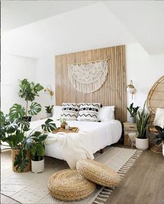 a bedroom with white bedding, plants and wicker baskets on the floor in front of it