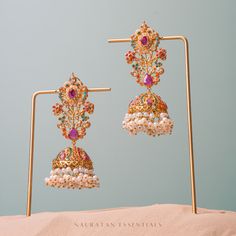 Emanate luxury and royalty in our Sara Earrings that can elevate any ensemble! A vibrant hued nauratan pair of earrings dispersed with brilliant stone work and is balanced with pearl moti clusters. Approximate earrings length is 3.5". Gold-plated on high-quality brass as base metal. Made by order. Kindly allow 5-7 weeks for the delivery of this item. For custom or urgent requests, please contact support@alacouture.com. *Please Note: The multi-colored beadwork might be slightly varying in pattern Fusion Style Jeweled Jhumkas For Festivals, Festive Fusion Jeweled Jhumkas, Jeweled Pearl Earrings For Festivals, Festive Fusion Style Jeweled Jhumkas, Jeweled Pearl Earrings For Festive Occasions, Jeweled Bridal Earrings For Reception And Festivals, Jeweled Earrings For Festivals, Festive Multicolor Earrings For Reception, Multicolor Chandbali Earrings For Reception