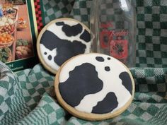 two decorated cookies sitting on top of a green and white checkered cloth next to a bottle