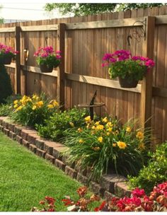 a wooden fence with flower pots on the top and flowers in the bottom, along side it