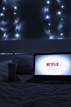 a laptop computer sitting on top of a bed in a room with lights above it