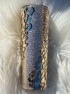 a blue and gold glitter tumbler sitting on white fur