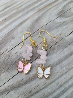 A pair of earrings with butterfly enameled charms and rose quartz chip beads. One butterfly is pink and the other white. Pink Butterfly Charm Earrings, Pink Butterfly Charm Dangle Jewelry, Pink Butterfly Charm Drop Earrings, Pink Dangle Jewelry With Butterfly Charm, Pink Dangling Charms Drop Earrings, Pink Drop Earrings With Butterfly Charm, Pink Drop Earrings With Dangling Charms, Pink Butterfly Charm Earrings As Gift, Pink Butterfly Charm Earrings For Gift