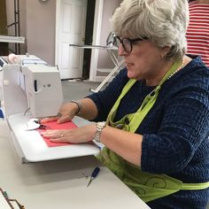 an older woman is using a sewing machine to sew something on a piece of paper