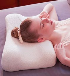 a woman laying on top of a white pillow