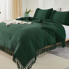 a green comforter with tassels and pillows