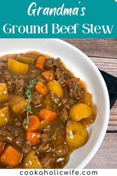 a white bowl filled with beef stew and carrots on top of a wooden table