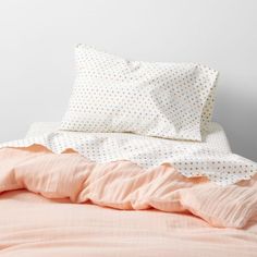 an unmade bed with pink sheets and polka dot pillow cases on top of it