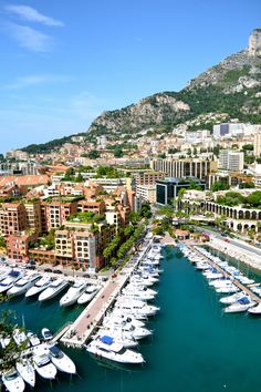 the boats are docked in the harbor next to the buildings and mountains that surround them