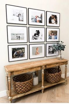 a wall with pictures and baskets hanging on it's side, next to a wooden table