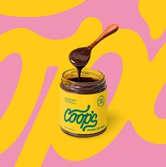 a jar of coffee with a spoon sticking out of it on a pink and yellow background