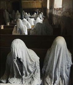 several statues covered in white cloths sitting on pews