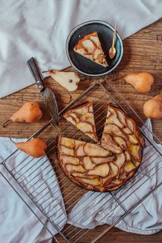 an apple pie on a cooling rack next to some pears and a slice missing