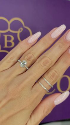 a woman's hand with two rings on her fingers and a pink manicure