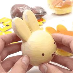 a person holding a small toy in front of doughnuts and donuts on a table