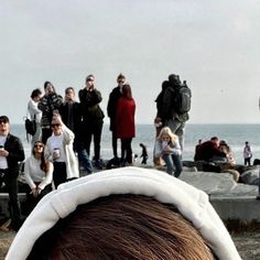 a group of people standing on top of a beach next to the ocean with one person wearing a head band