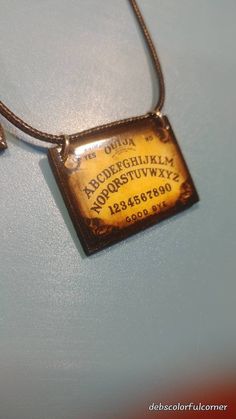 Thank you for looking at my miniature Ouija board necklace.  I hand make these cute necklaces that would look really cute hanging in your car too.  This would make a really cute one of a kind gift for a special friend.  The wooden miniature ouija board measures 1 X 1 1/2 inch. These are only one sided. I coated this necklace with resin. I used a ruler in the picture so you can see the size. Contact me if you have any questions.   These can very slightly from the pictures. I always add a couple v Wooden Miniature, Cute Necklaces, Klamath Falls, Pixel Heart, Spirit Board, Ouija Board, Triangle Necklace, Blue Tassel, Black Rope