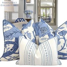 blue and white pillows on a couch in front of a mirror with shuttered windows