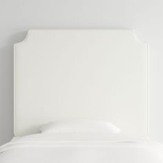 the headboard of a bed with white sheets and pillows