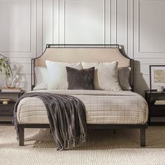 a bedroom with a bed, nightstands and pictures on the wall behind it is shown