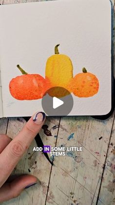 someone is drawing pumpkins on a notebook with watercolor pencils and paper scissors