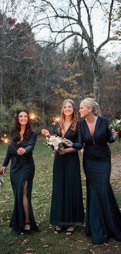 three women in long black dresses standing next to each other with sparklers coming out of their mouths