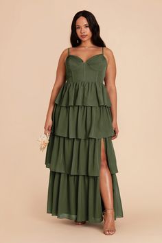 a woman wearing a green dress with tiered layers and a slit down the side