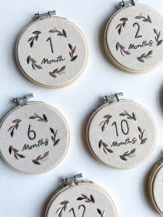 six embroidered hoops with numbers and arrows on them, each showing the number one month