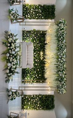 an indoor wedding setup with white flowers and greenery on the wall, surrounded by chairs