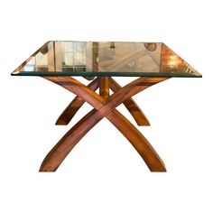 a wooden table with glass top and two cross legs on the bottom, against a white background