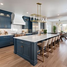 a large kitchen with blue cabinets and an island in the middle is surrounded by wooden flooring