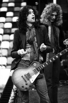 two men standing next to each other with guitars