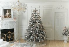 a decorated christmas tree in the corner of a room with fireplace and chandelier