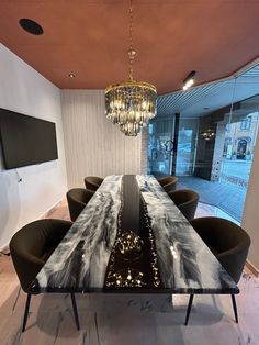 a dining room table with chairs and a chandelier hanging from the ceiling