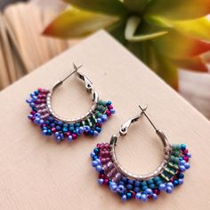 Stainless steel hoops encircled with glass beads in shades of fuscia, blue and iridescent violet. These handmade earrings add a bright pop of color to any outfit and make a great gift. 1 inch diameter stainless steel hoops.  Total diameter with beads = 1.25 inches. Nickel Free Multicolor Metal Hoop Earrings, Nickel-free Multicolor Metal Hoop Earrings, Multicolor Small Hoop Metal Earrings, Nickel-free Small Hoop Metal Beaded Earrings, Nickel-free Metal Hoop Beaded Earrings, Blue Beaded Metal Hoop Earrings, Handmade Multicolor Metal Hoop Earrings, Small Hoop Earrings With Colorful Beads In Blue, Multicolor Metal Hoop Jewelry