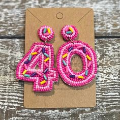 a pair of pink beaded earrings on top of a piece of cardboard with the number forty