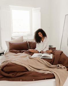 a woman sitting on her bed reading a book