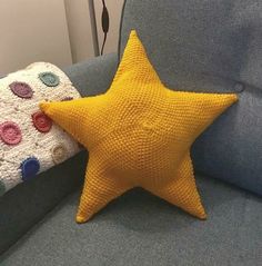 a yellow star pillow sitting on top of a gray couch next to a blue chair