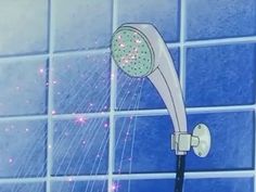 the shower head is spraying water from it's sprinkles in front of a blue tiled wall