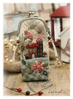 a small purse with flowers and houses on it, sitting on top of a wooden table