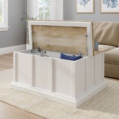 a white storage box sitting on top of a rug in front of a couch and window