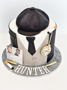 a hat and tie on top of a cake that is decorated like a man's suit