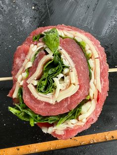 a sandwich with meat, lettuce and other toppings sitting on top of a black surface