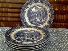 a stack of blue and white plates sitting on top of a table next to books