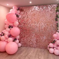 pink balloons and greenery are arranged in the corner of a room that is decorated with sequins